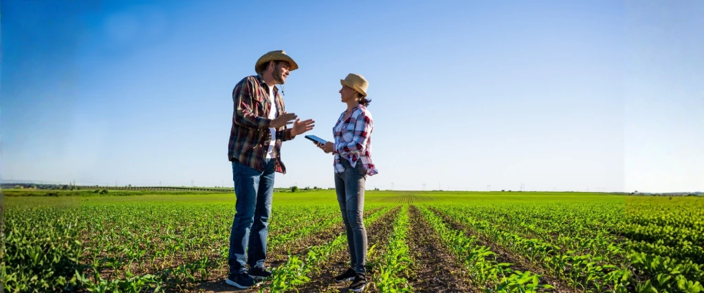 Un homme et une femme discutent d'outils dans un paysage de champ cultivé